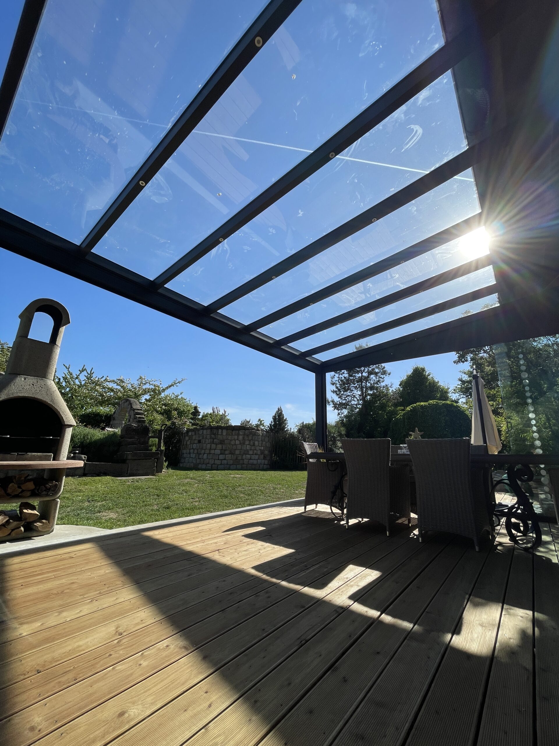 Terrassenüberdachung mit Glasdach und Holzboden im Garten