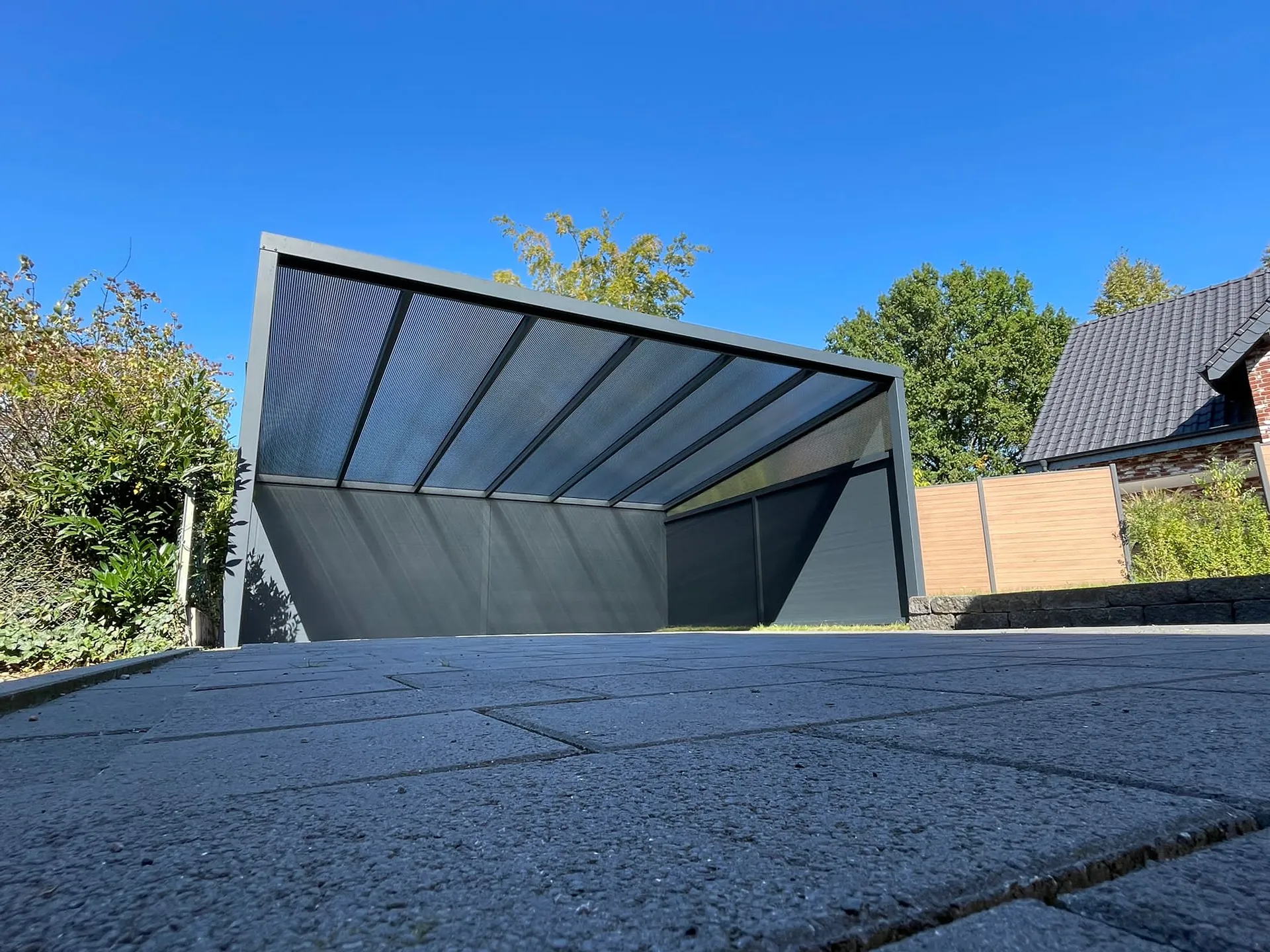 Moderner Aluminium-Carport mit transparentem Dach und seitlichem Sichtschutz