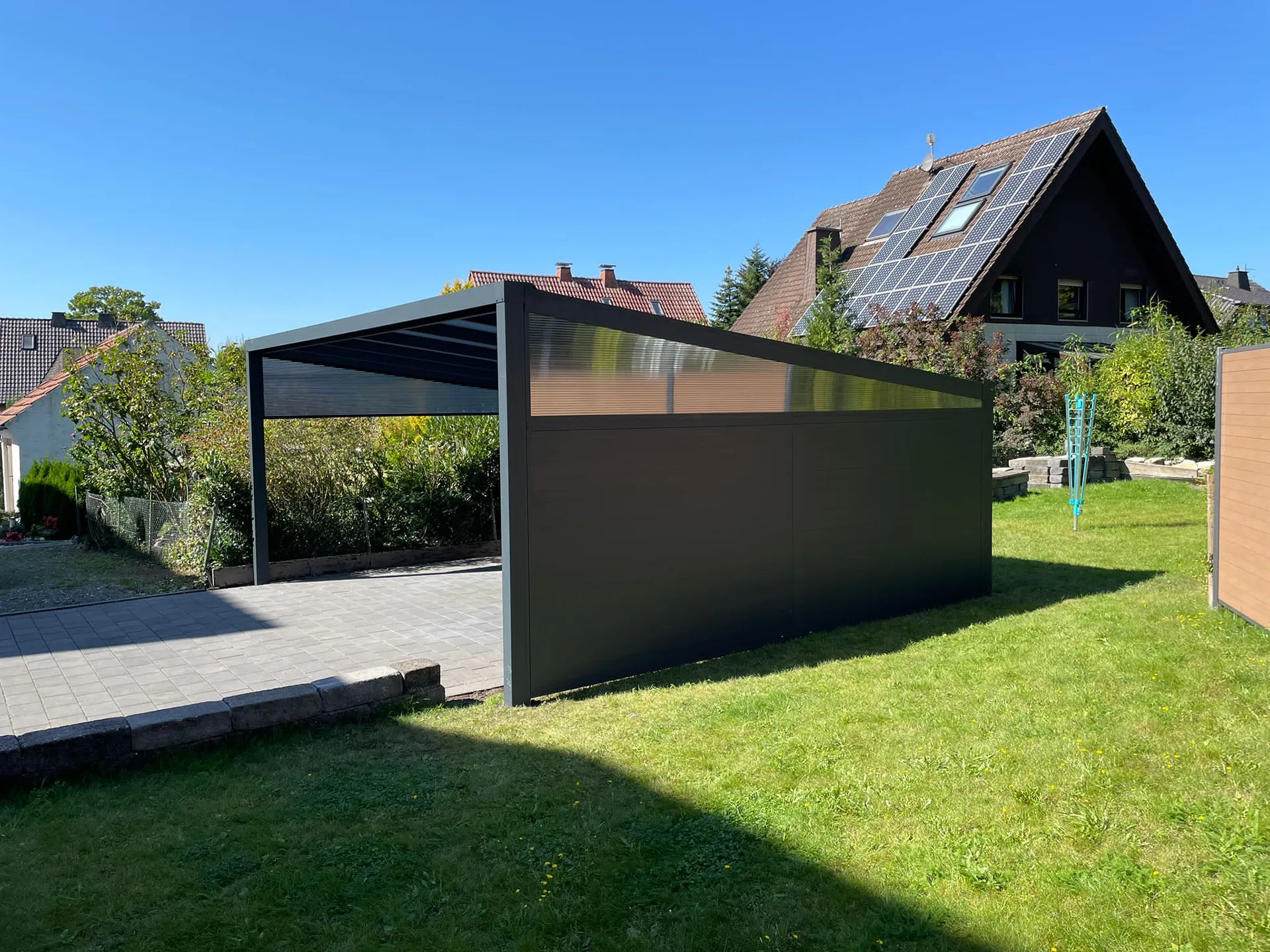 Freistehendes Carport mit Sichtschutzwand im modernen Garten