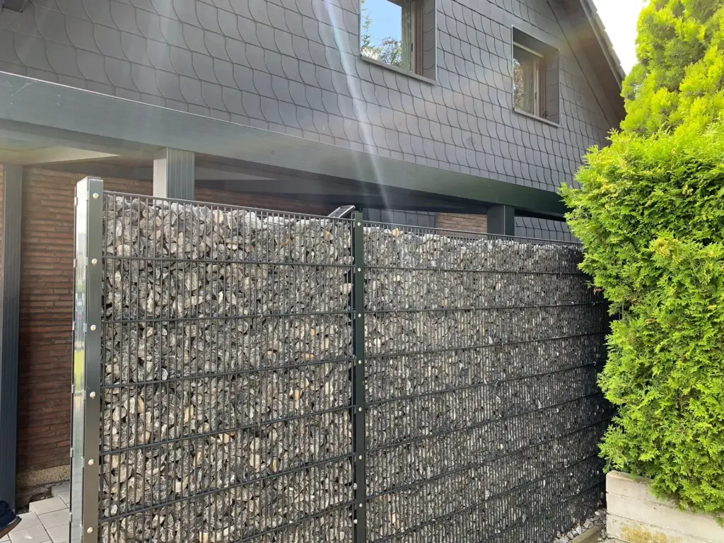 Gabionenzaun als Sichtschutz mit Metallgitter und Steinfüllung am Haus
