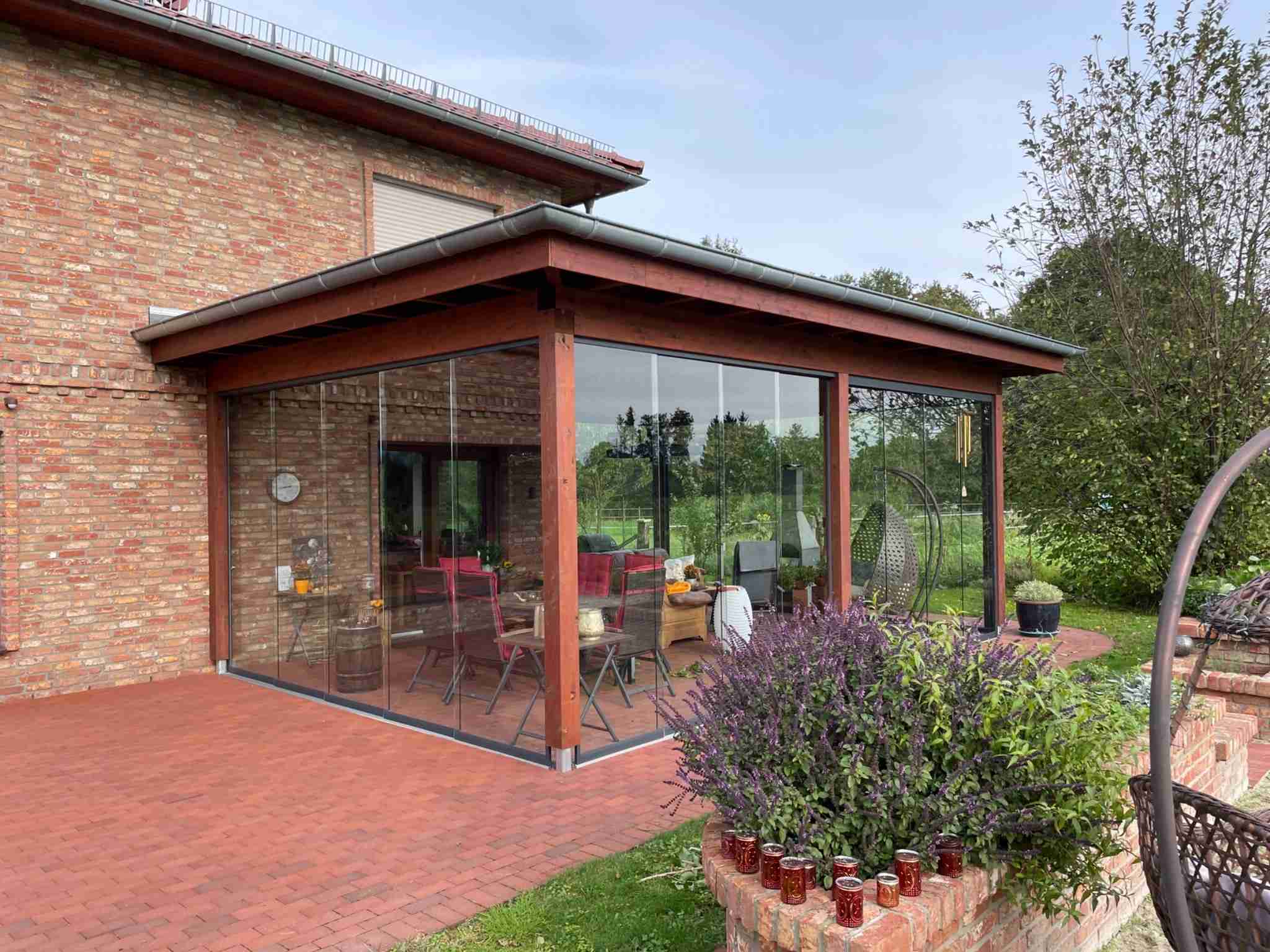 Terrassenüberdachung mit Holzrahmen und Glasschiebewänden an einem Einfamilienhaus