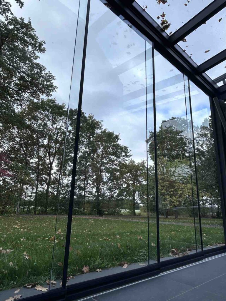 Glas-Schiebewände einer Terrassenüberdachung mit Blick in den Garten
