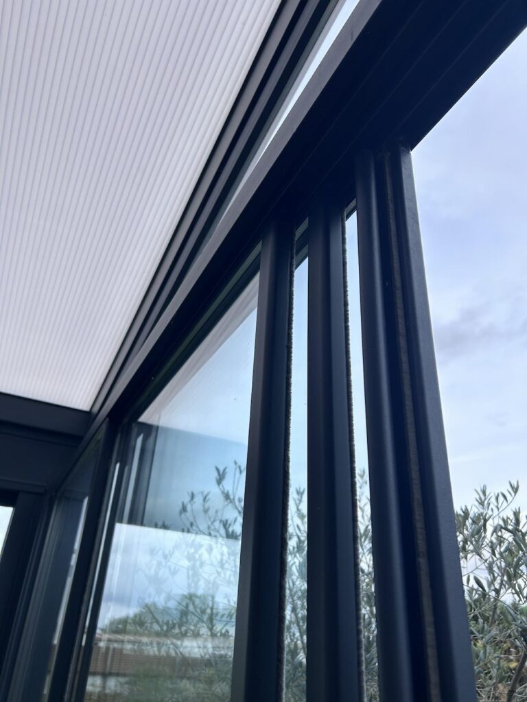 Detailaufnahme von Glasschiebetüren mit Aluminiumprofilen unter einer Terrassenüberdachung