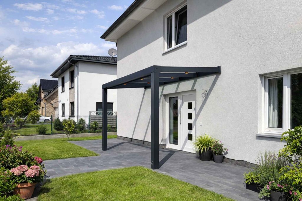 Moderne Eingangsüberdachung aus Aluminium mit Beleuchtung vor weißem Einfamilienhaus