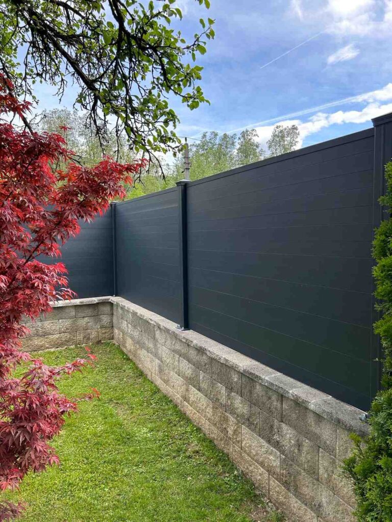 Moderner Sichtschutzzaun aus Aluminium im Garten mit Steinmauer