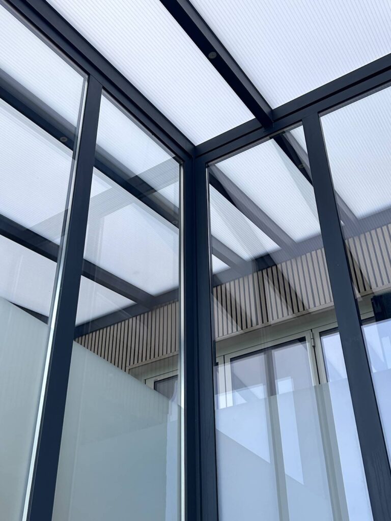 Detailaufnahme einer Terrassenüberdachung mit Aluminiumrahmen und milchigem Glasdach