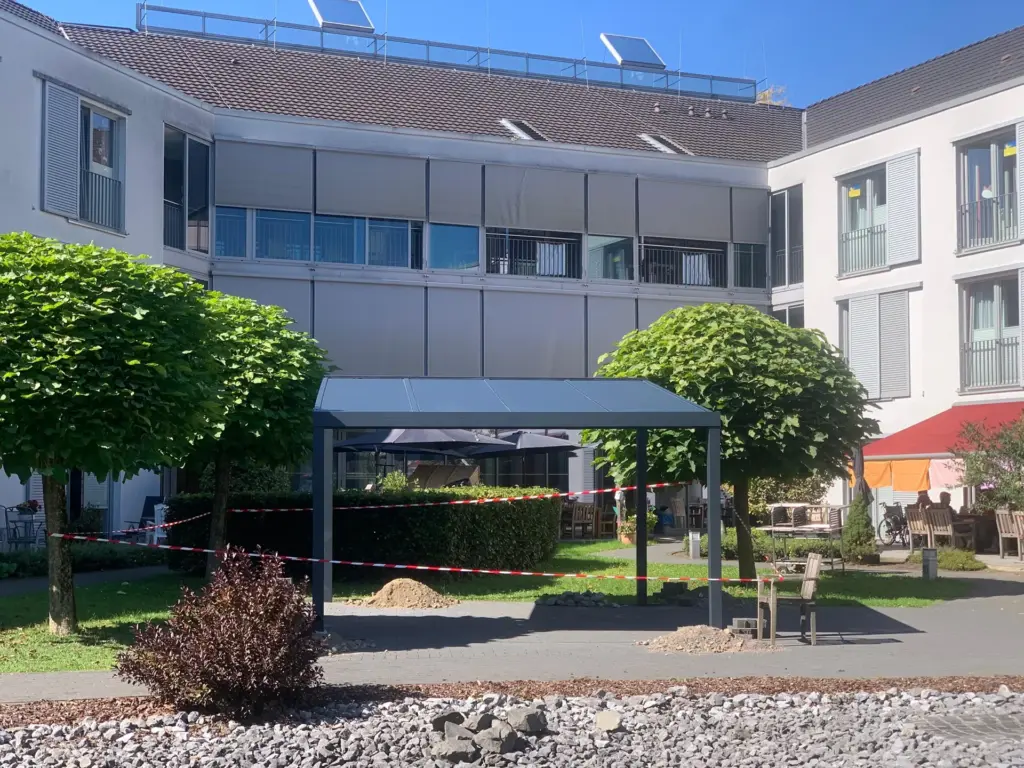 Freistehende Aluminium-Terrassenüberdachung in Innenhof einer Wohnanlage