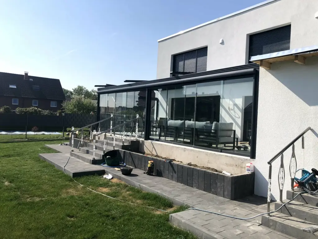 Kaltwintergarten mit Glas-Schiebeanlage entlang einer erhöhten Terrasse am modernen Haus