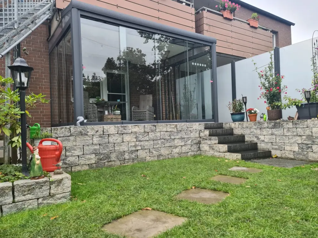 Kaltwintergarten mit Glasschiebetüren und Aluminiumrahmen auf erhöhter Terrasse