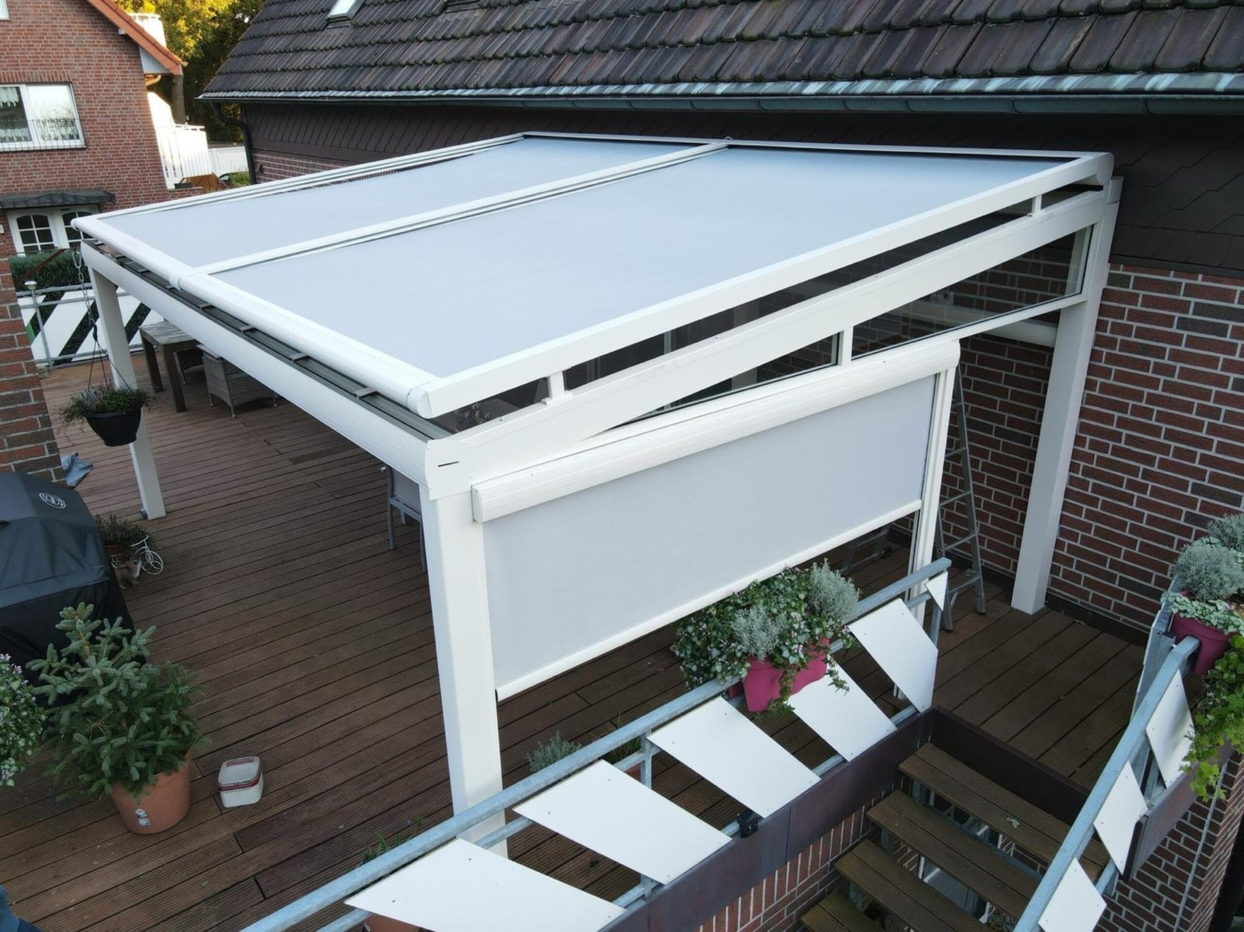 Terrassenüberdachung aus Aluminium mit Milchglasdach und seitlichem Sichtschutz auf Holzterrasse