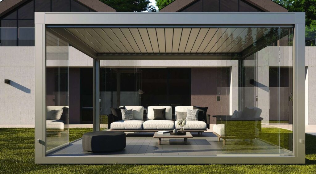 Geschlossene Pergola mit Glaswänden und Lamellendach als moderner Outdoor-Wohnraum