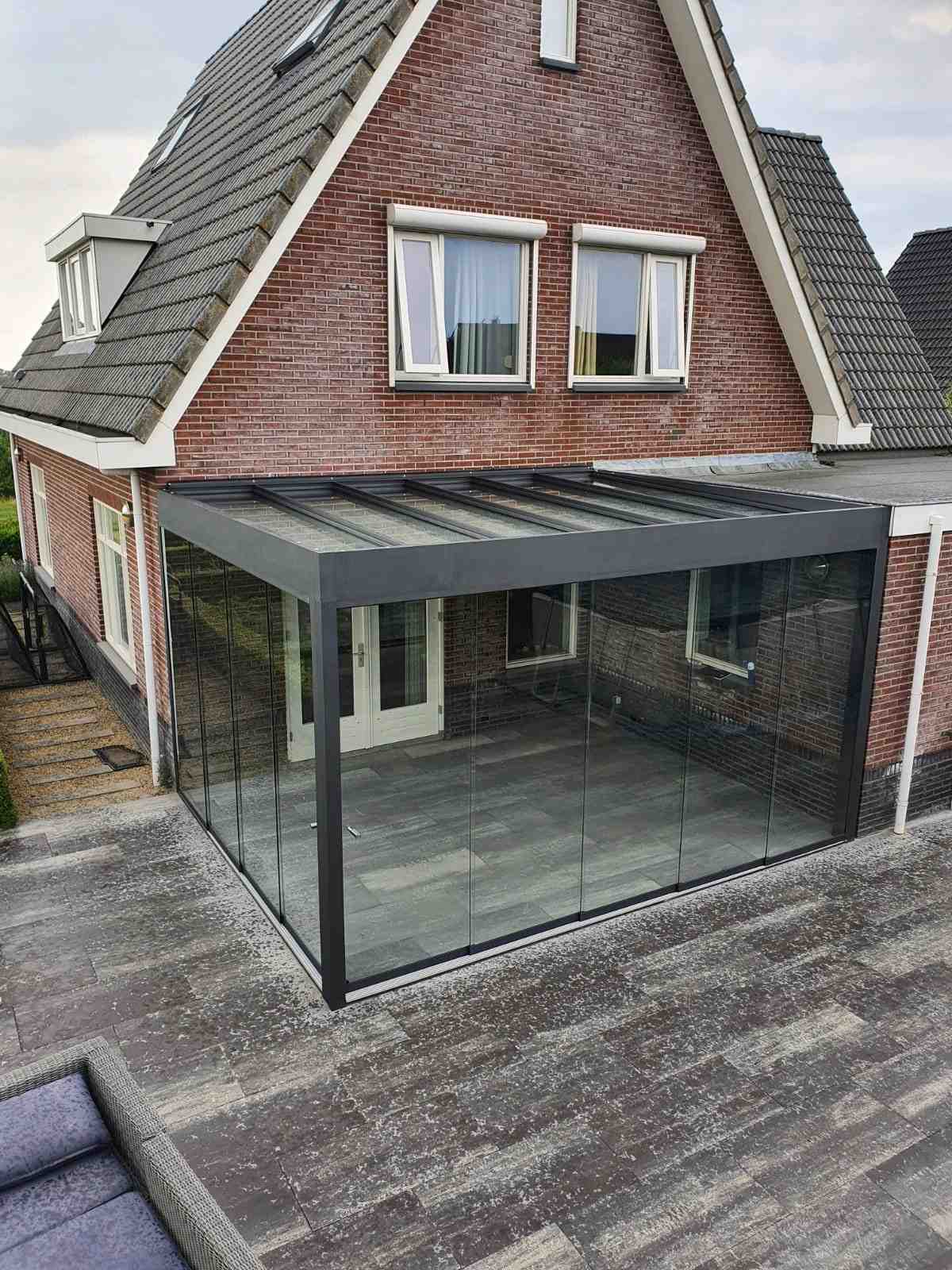 Terrassenüberdachung mit Glaswänden an Backsteinhaus für ganzjährige Nutzung