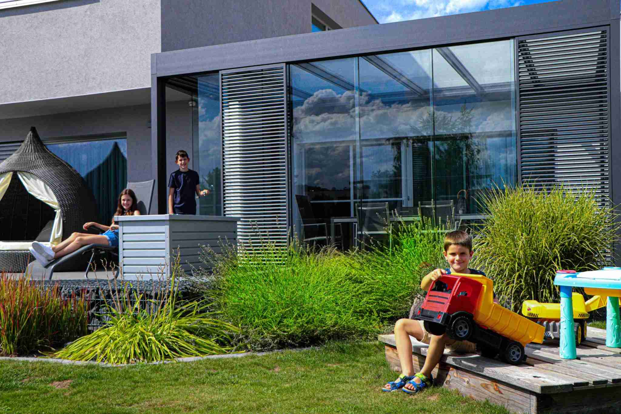 Terrassenüberdachung mit Glas und Schiebeläden im modernen Garten