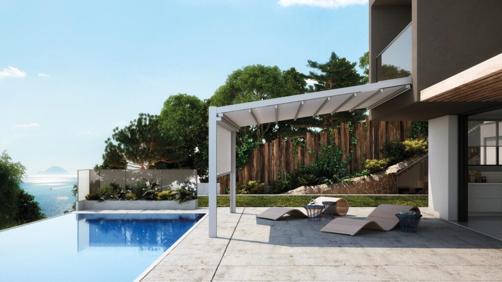 Anbau-Pergola mit Lamellendach neben einem Pool mit Meerblick