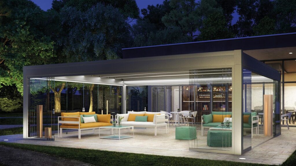 Pergola mit Lamellendach und Glas-Schiebeanlagen bei Nacht, beleuchteter Outdoor-Loungebereich