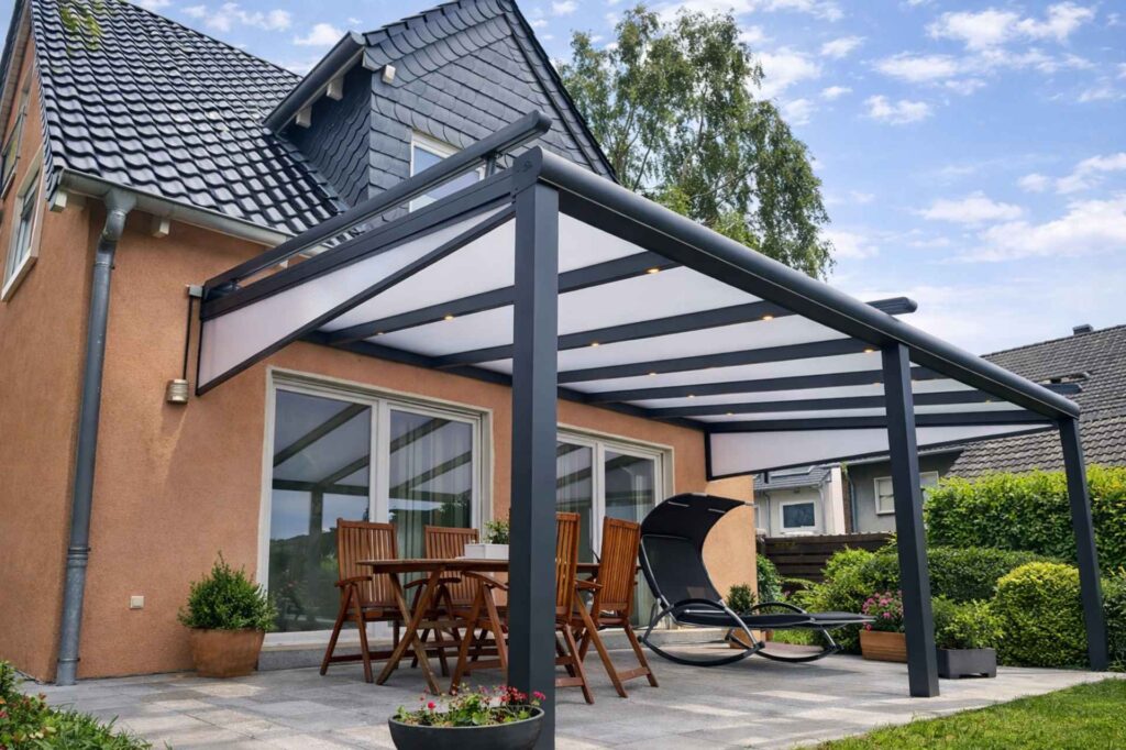 Moderne Aluminium-Terrassenüberdachung mit Milchglasdach und Sitzbereich vor Einfamilienhaus