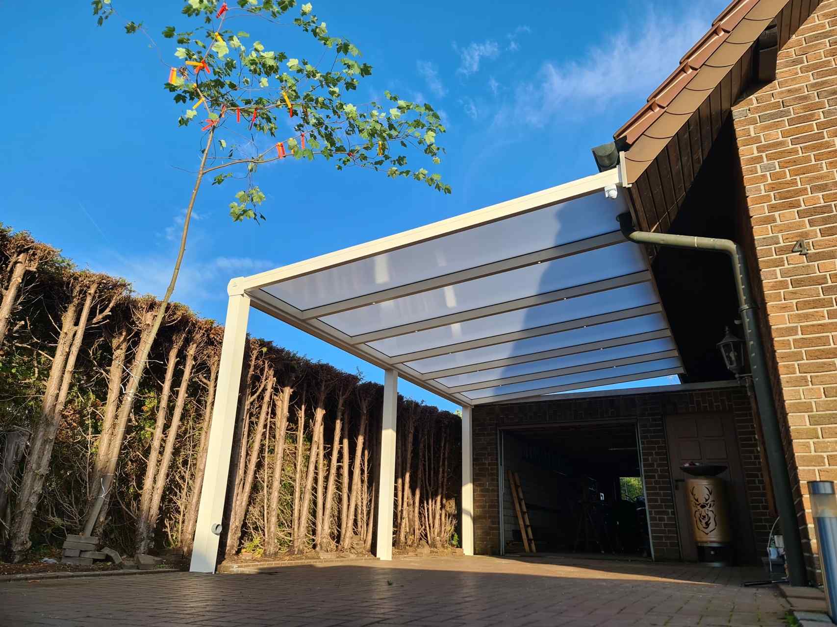 Carport aus Aluminium mit transparentem Dach an einem Einfamilienhaus