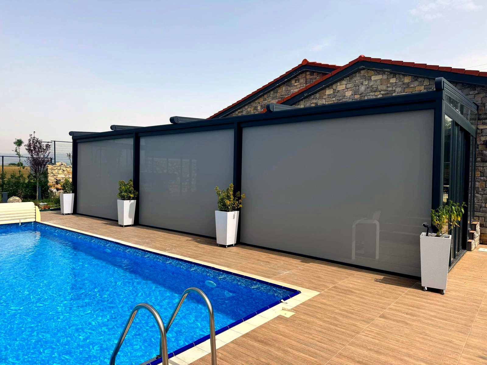 Terrassenüberdachung mit Senkrechtmarkisen und Glasschiebewänden am Pool