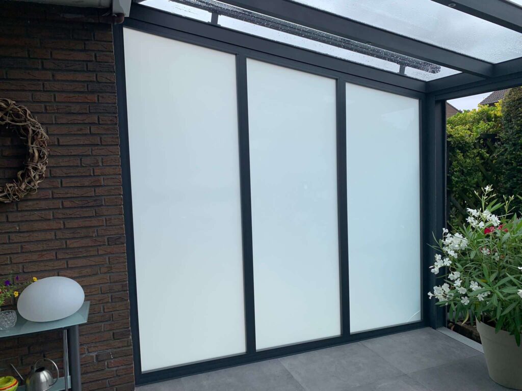 Terrassenüberdachung mit satinierten Schiebeelementen aus Glas und Aluminiumrahmen