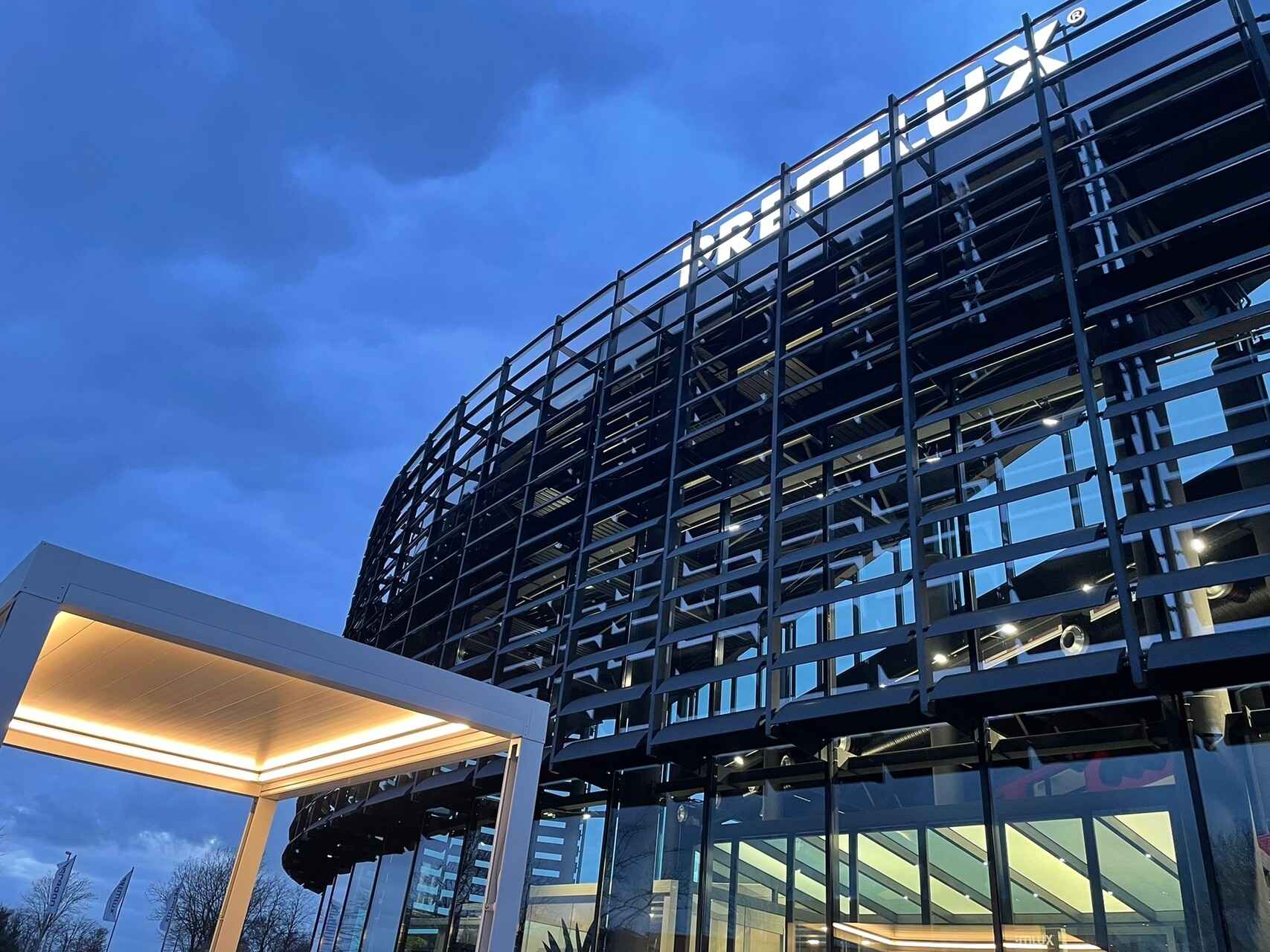 Moderne Fassade des PREMLUX Showrooms bei Abenddämmerung mit beleuchtetem Schriftzug