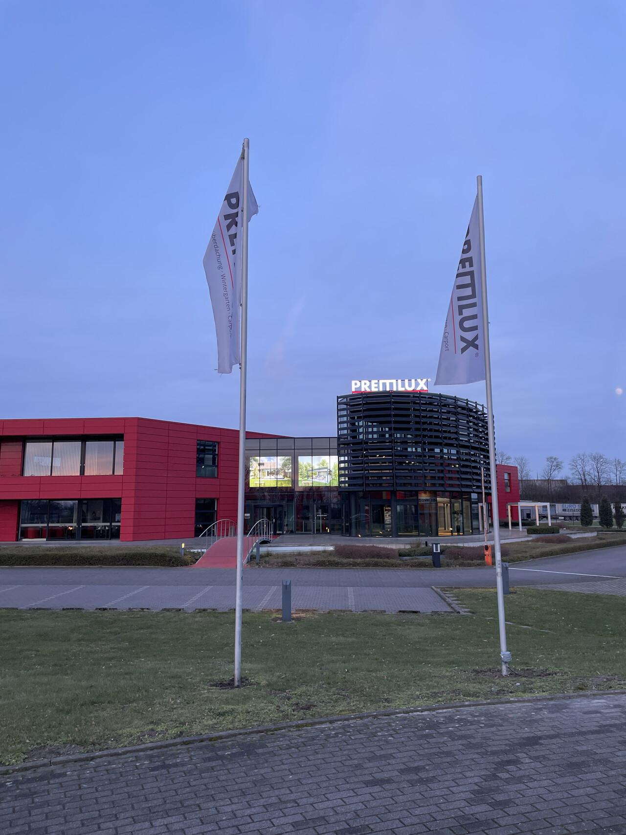 Außenansicht des PREMLUX Showrooms mit moderner Architektur und Fahnen vor dem Gebäude