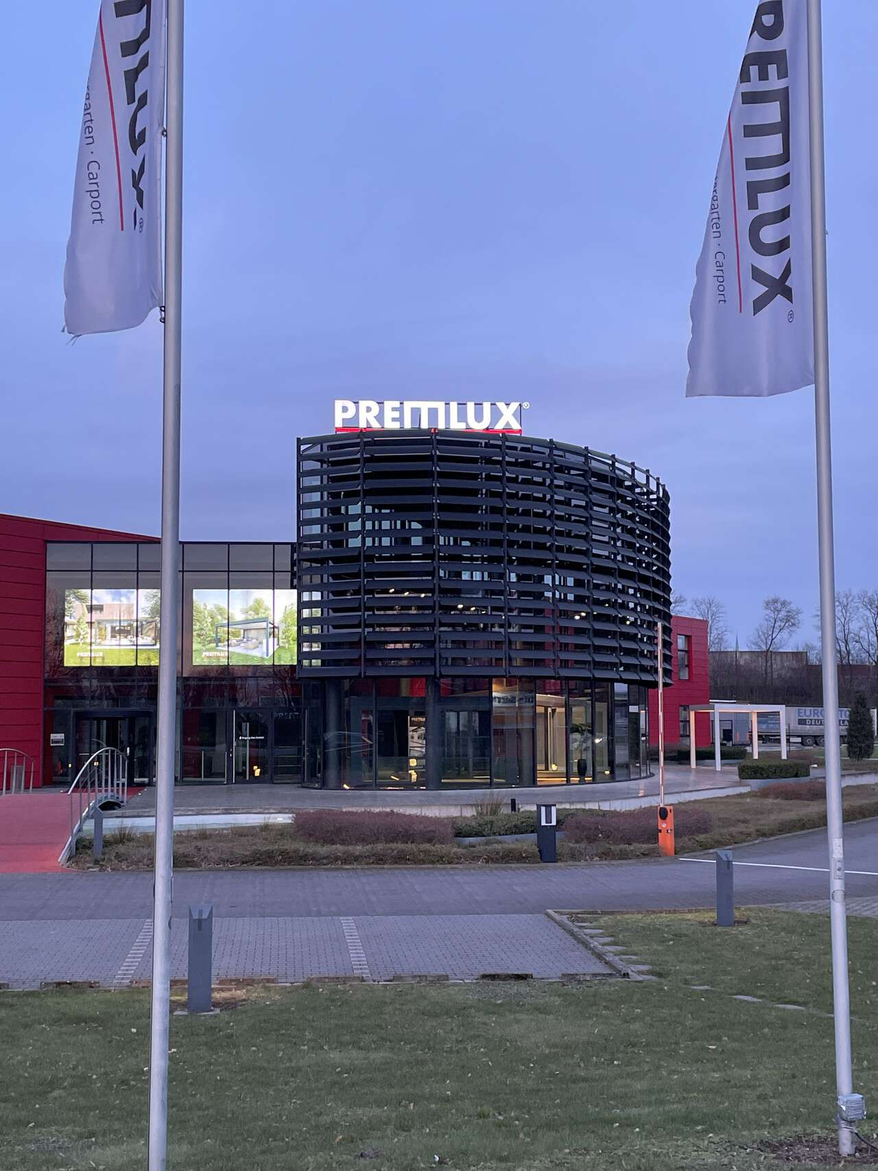 Außenansicht des PREMLUX Showrooms mit moderner Architektur und Fahnen vor dem Gebäude