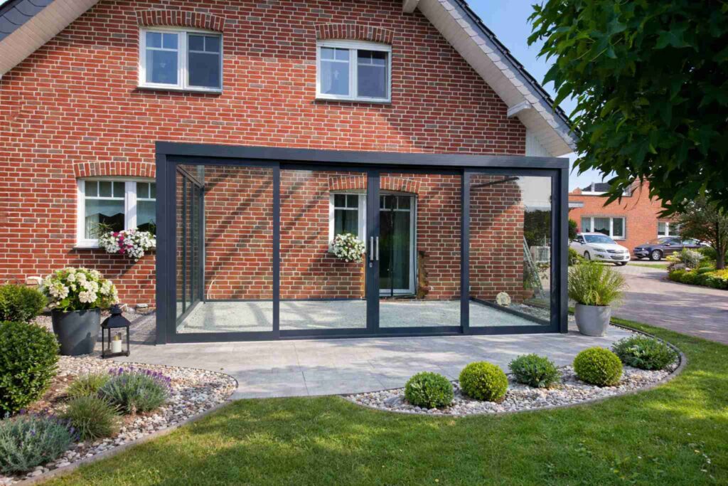 Moderne Terrassenüberdachung mit Glas-Schiebeelementen an einem Einfamilienhaus aus Backstein
