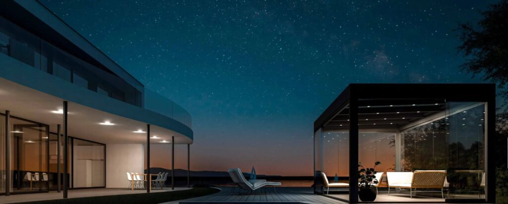 Moderne Terrassenüberdachung mit Glas und Beleuchtung bei Nacht im Garten
