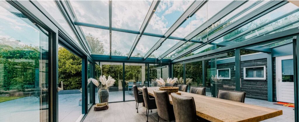 Moderne Terrassenüberdachung mit Glasdach und Schiebewänden als Essbereich im Garten