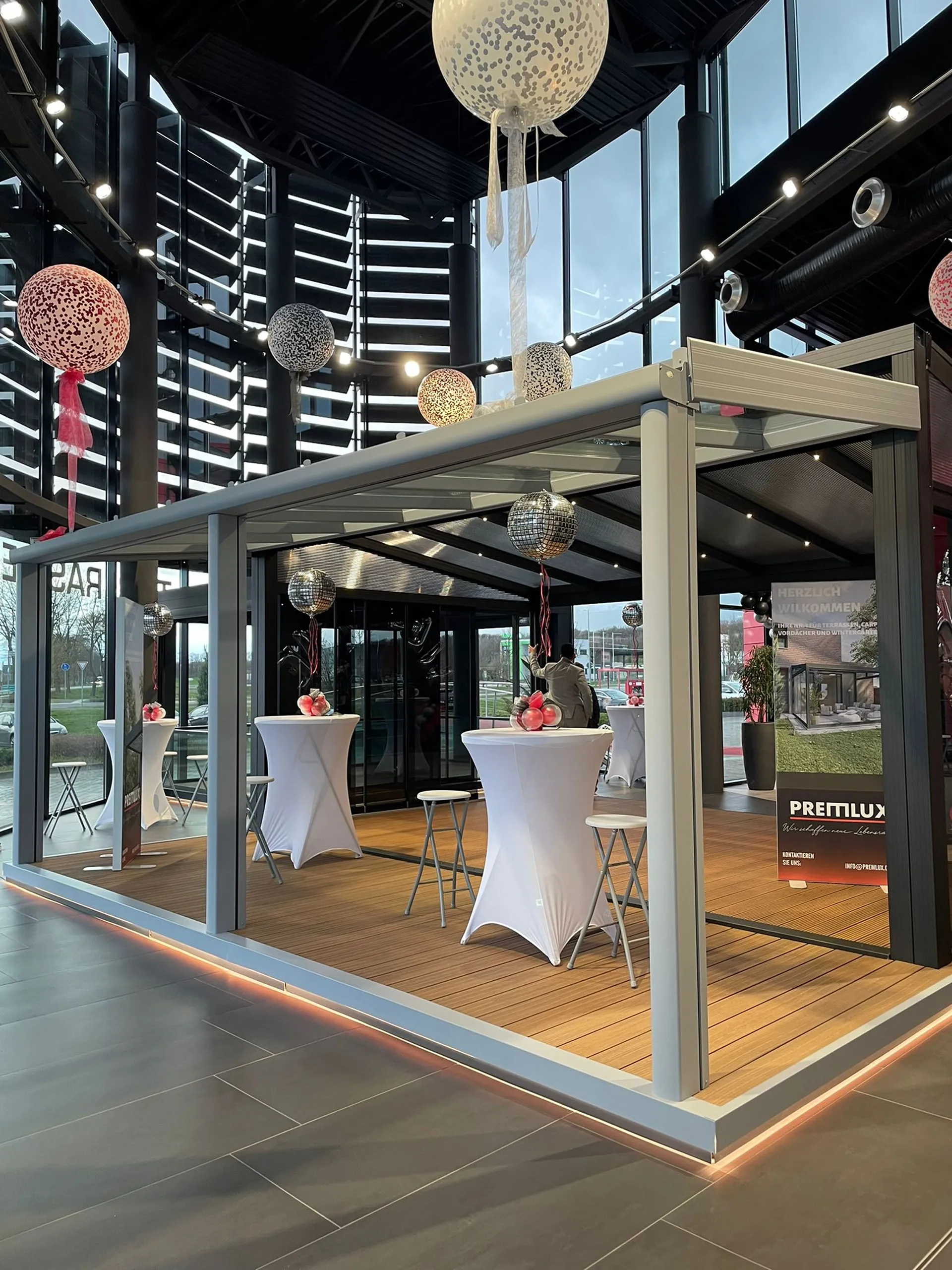 Terrassenüberdachung als Ausstellungssystem im Innenbereich mit Beleuchtung und Glaswänden