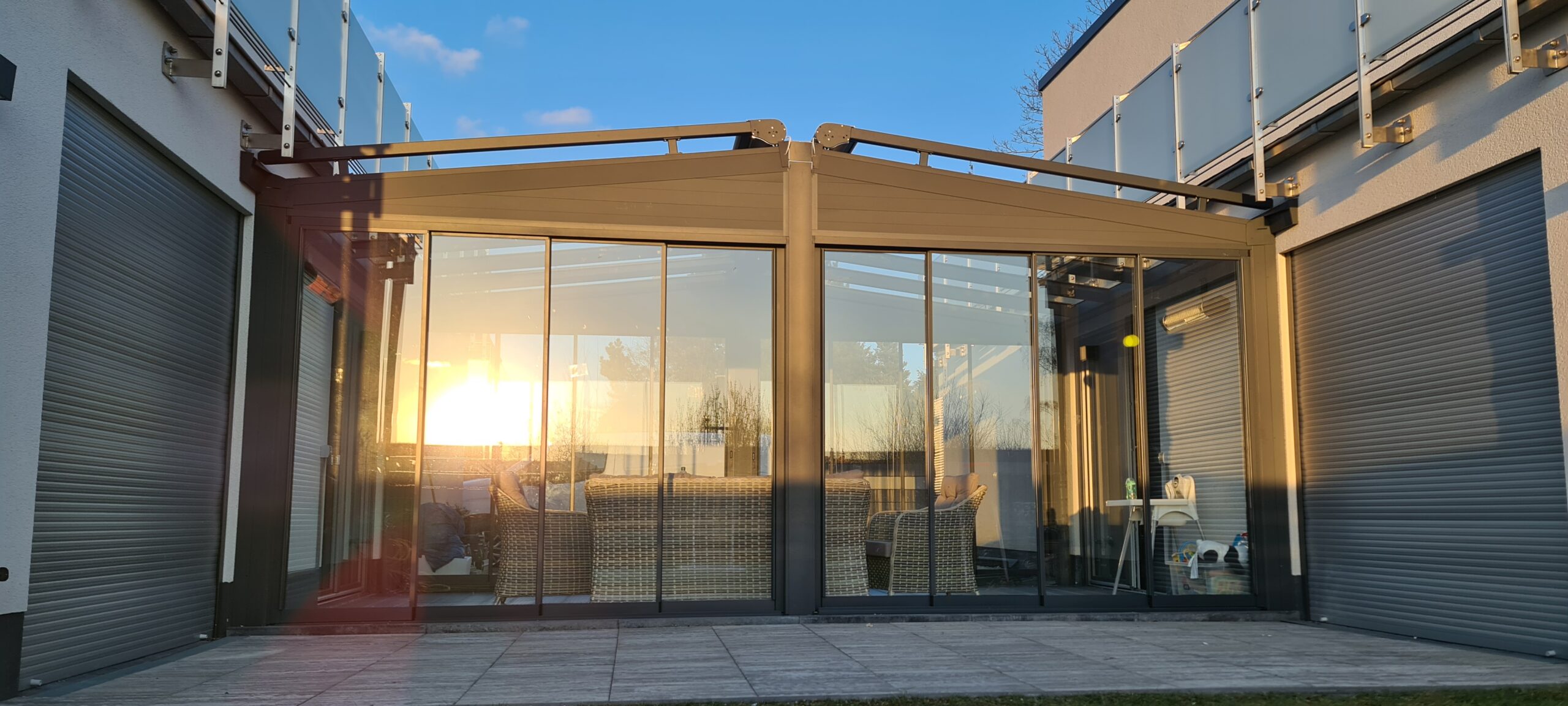 Terrassenüberdachung mit Glasschiebeanlage und Aluminiumrahmen bei Sonnenuntergang