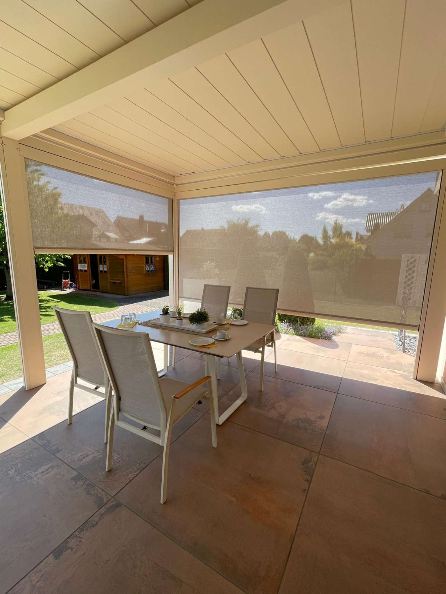Überdachte Terrasse mit seitlichen Sonnenschutzrollos und Essbereich