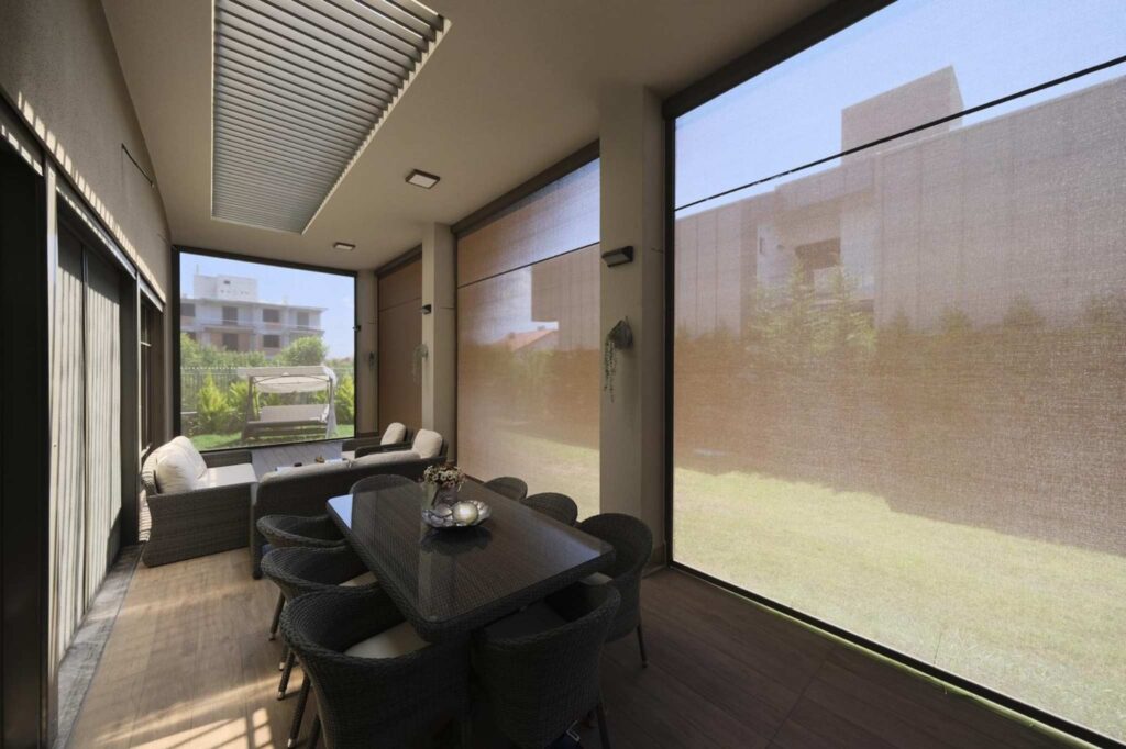 Überdachte Terrasse mit Lamellendach und seitlichen Sonnenschutzsystemen