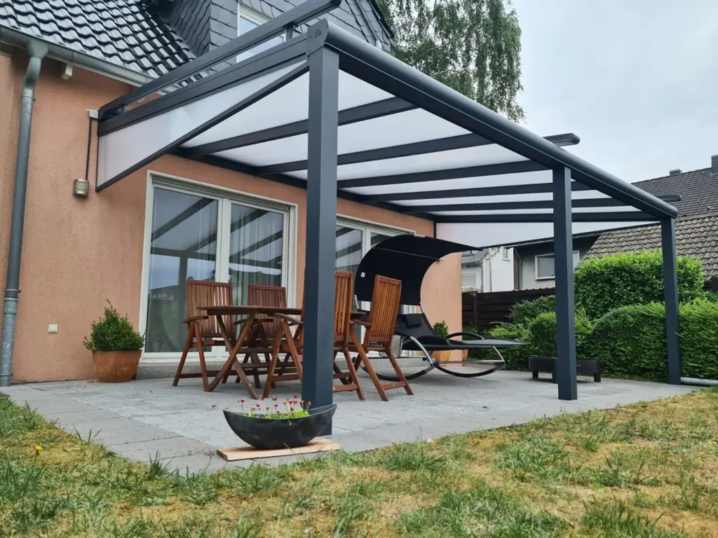 Aluminium Terrassenüberdachung mit Milchglasdach und Sitzgruppe im Garten