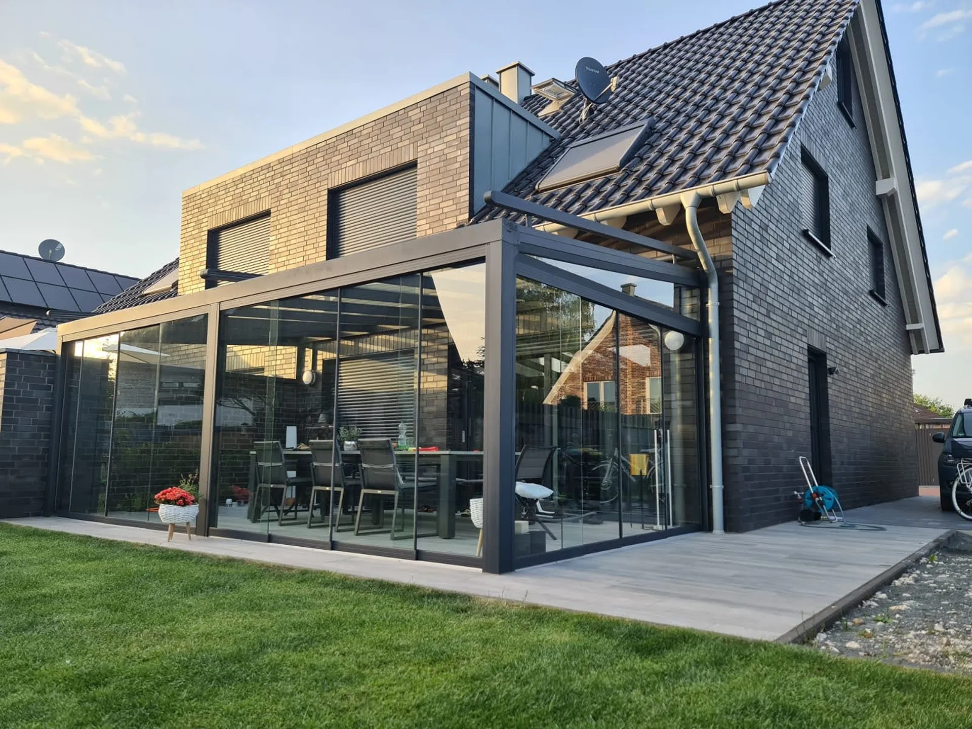 Großzügige Terrassenüberdachung mit Glasschiebetüren an modernem Einfamilienhaus