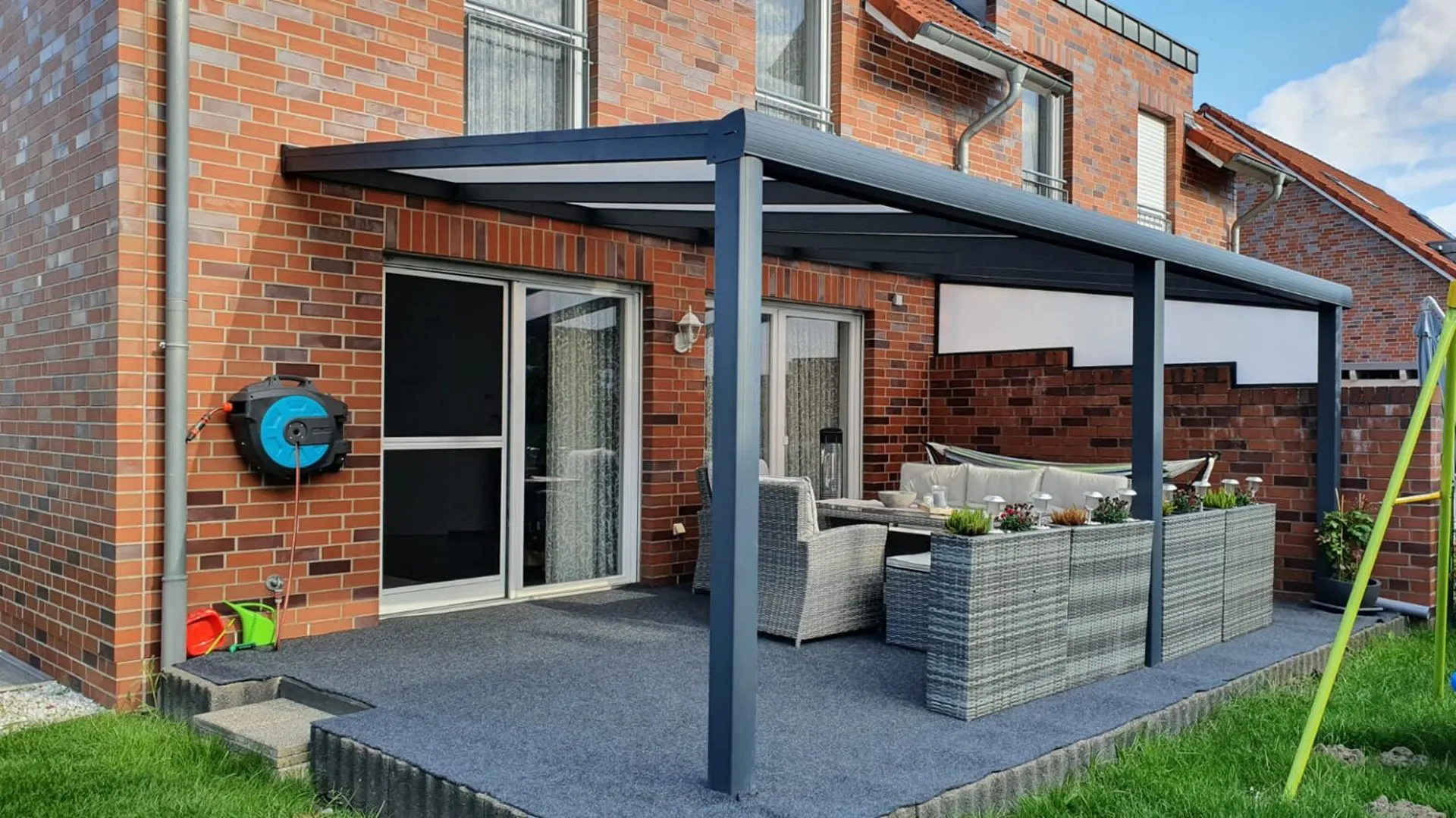 Terrassenüberdachung aus Aluminium mit integriertem Sonnenschutz an Reihenhaus