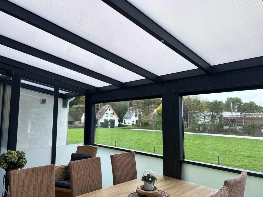 Innenansicht einer Terrassenüberdachung mit geschlossenem Dach und großen Fensterflächen