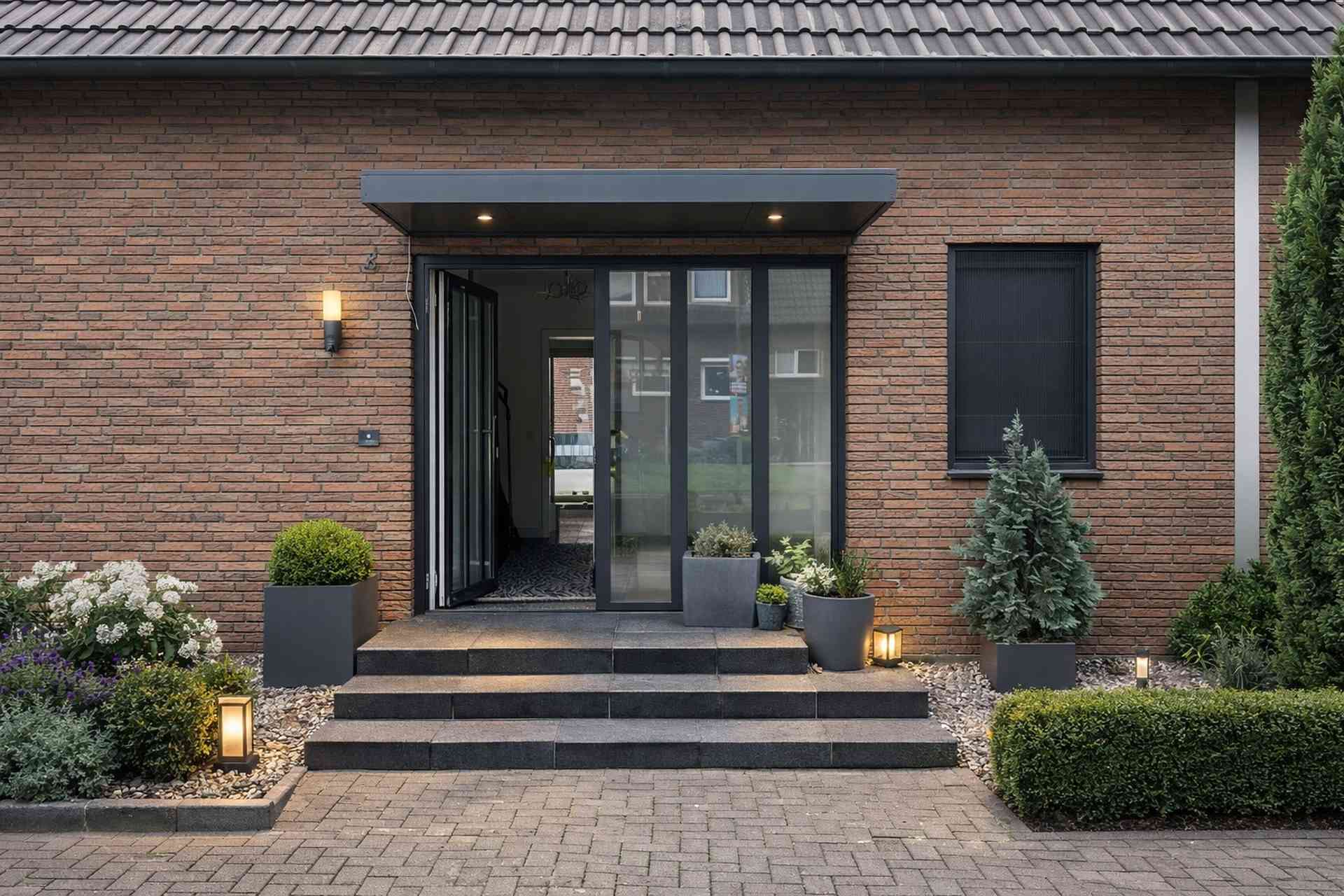 Eingangsüberdachung aus Aluminium mit Beleuchtung an moderner Backsteinfassade