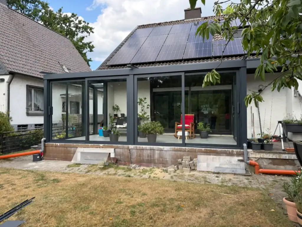 Terrassenüberdachung aus Glas über Eck mit Glasschiebetüren an einem Einfamilienhaus in Oer-Erkenschwick